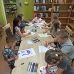 zajęcia edukacyjne w bibliotece, dzieci przy stole malują portret mamy