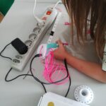 dziewczynka wykonuje ozdobę długopisem 3D