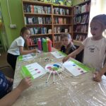 zajęcia w bibliotece dzieci przy stole malują farbami
