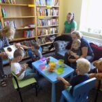czytanie dla dzieci w bibliotece dzieci i dorośli siedzą wokół stołu