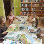 Biblioteka zajęcia edukacyjno-czytelnicze dzieci siedzą przy stole, czytają