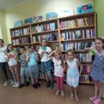 Biblioteka zajęcia edukacyjno-czytelnicze dzieci stoją przed regałami z książkami