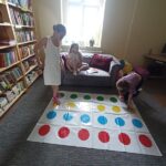 Biblioteka zajęcia edukacyjno-czytelnicze dzieci grają w grę rozłożoną na podłodze