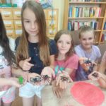 Biblioteka zajęcia edukacyjno-czytelnicze dzieci pokazują na dłoniach owady