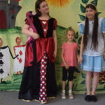 dziewczynka stoi z aktorami ze spektaklu "Alicja w Krainie Czarów"