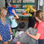 grupka dzieci szukająca przebrań w kolorowych perukach