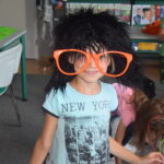 dziewczynka w peruce i dużych kolorowych okularach