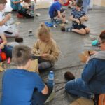 czytanie na spontanie, grupa dzieci siedzi na podłodze owija wełną misie z tektury