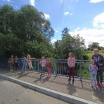 zajecia edukacyjno-czytelnicze, dzieci na spacerze stoją przy barierce wśród zieleni