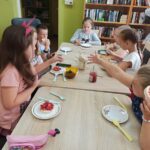 zajecia edukacyjno-czytelnicze, dzieci siedzą przy stole i jedza