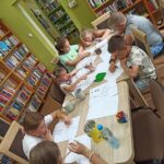 zajecia edukacyjno-czytelnicze, dzieci przy stole rysują