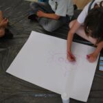 czytanie z Bolkiem i Lolkiem, grupy dzieci siedzą na podłodze i rysują