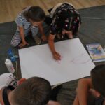 czytanie z Bolkiem i Lolkiem, grupy dzieci siedzą na podłodze i rysują