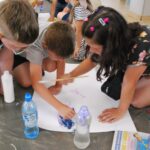 czytanie z Bolkiem i Lolkiem, grupy dzieci siedzą na podłodze i rysują kolorowm pisakiem