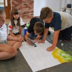 czytanie z Bolkiem i Lolkiem, grupy dzieci siedzą na podłodze i rysują kolorowm pisakiem
