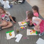 czytanie na spontanie, czytanie z reksiem, grupa dzieci maluje worki lniane farbami