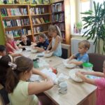 zajęcia dla dzieci w filii bibliotecznej, dzieci przy stole mieszają w miskach składniki