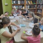 zajęcia dla dzieci w filii bibliotecznej, dzieci przy stole mieszają w miskach składniki