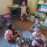 dzieci siedzą na dywanie i grają w grę