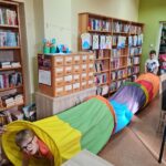 wnętrze biblioteki dzieci przechodzą przez kolorowy długi tunel