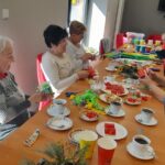 Seniorki siedzą przy stole, na stole materiały plastyczne