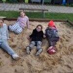 plac zabaw, cztery dziewczynki siedza w piaskownicy