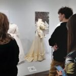 grupa młodzieży ogląda wystawę sukni ślubnych z 19 wieku