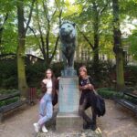dwie dziewczyny pozują z rzeźbą lwa