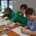 zajęcia zrtystyczne dla seniorów, grupa maluje przy stole