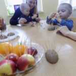 dzieci wraz z rodzicami robią jeże z owoców i wykałaczek