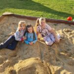 troje dzieci pozuje w piaskownicy do zdjęcia