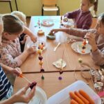 dzieci przy stole robią szaszłyki z warzyw