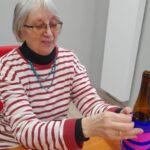 seniorka okleja butelkę bibułą