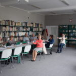 grupa seniorów siedzi przy stołach i wykonują ćwiczenia na pamięć i koncetrację