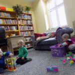 troje dzieci bawi sią w bibliotece