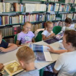 grupa dzieci siedzą przy stołach i oglądają książki o morzu i morskich zwierzętach