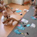 dzieci siedzą na dywanie i szyją lamy z materiały