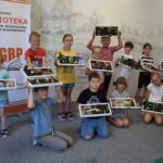 grupa dzieci stoi ze swoimi pracami artystycznymi "Lato w ramce"
