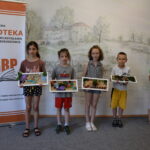 grupa dzieci stoi ze swoimi pracami artystycznymi "Lato w ramce"