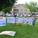grupa dzieci stoi ze swoimi namalowanymi farbami obrazami
