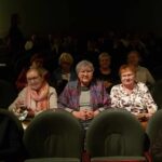 grupa seniorów siedzi na widowni w teatrze