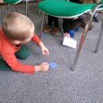 dziecko szuka koperty pod krzesłem