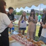 Projekt młodzieżowy Ziołowe love - młodzież stoi wokół stołu z deserkami