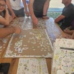 Projekt młodzieżowy Ziołowe love -na stole puzzle, kilka osób wokół układa je