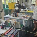 Warsztaty malarskie, młodzież maluje przy stołach i sztalugach