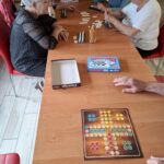 Grupa seniorów siedzi przy stole i gra w gry planszowe