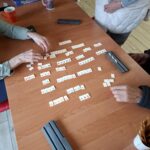 Grupa seniorów siedzi przy stole i gra w gry planszowe