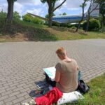 park, kobieta siedzi na trawniku, maluje