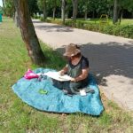 park, kobieta siedzi na kocu, maluje