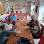 Grupa seniorów siedzi przy stole i gra w gry planszowe